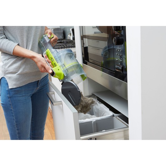 Photo of BLACKDECKER CUA525BHA vacuum canister being emptied into a kitchen trash bin.
