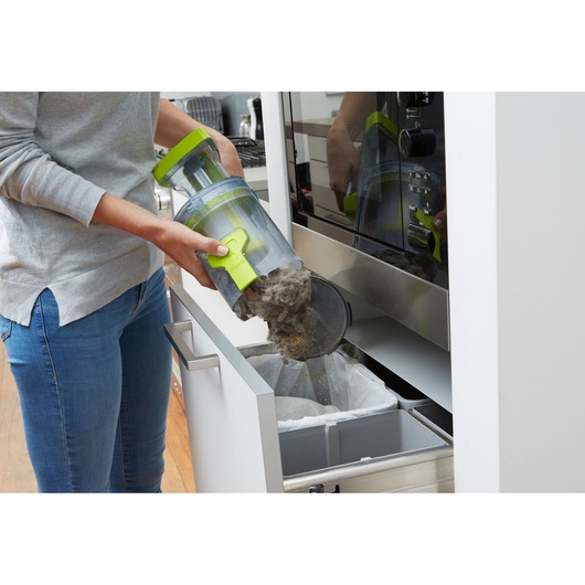 BLACKDECKER CUA525BHA vacuum dust container being emptied into a kitchen trash bin.