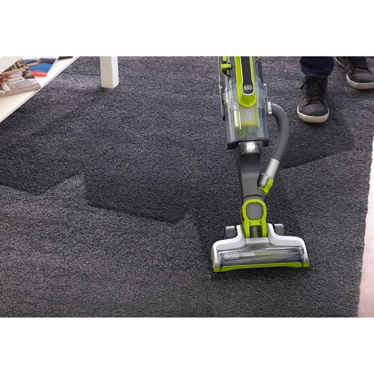 BLACKDECKER CUA525BHA upright vacuum cleaner cleaning dark carpet, front angle view.