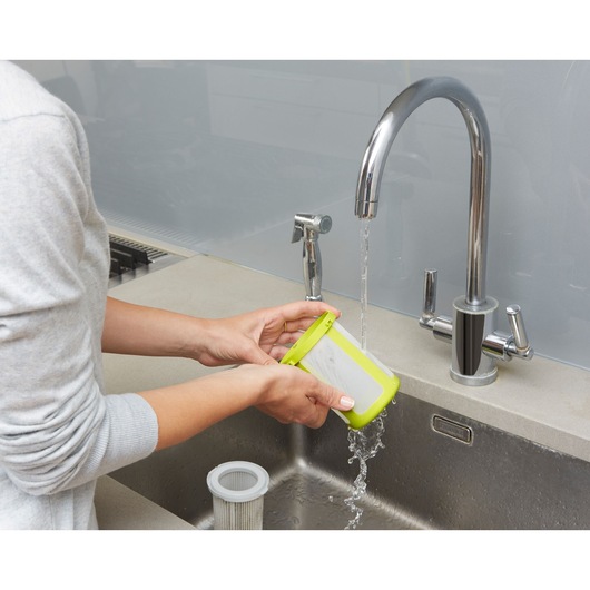 BLACKDECKER CUA525BHA vacuum filter being rinsed under a kitchen faucet in close-up.