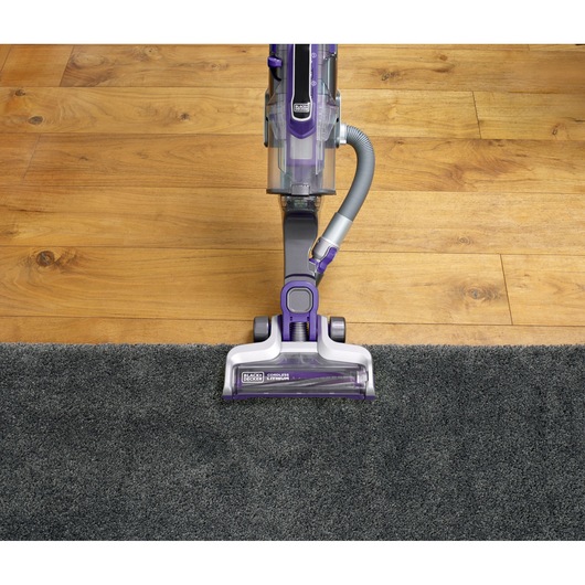 BLACKDECKER CUA525BHP upright cordless vacuum cleaner on grey carpet and wood floor, top view.
