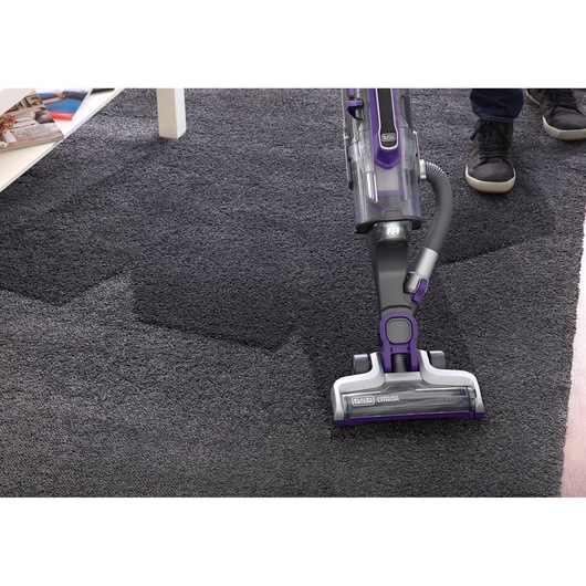 Photo of BLACKDECKER CUA525BHP vacuum cleaner in use on dark carpet, showing cleaning efficiency.