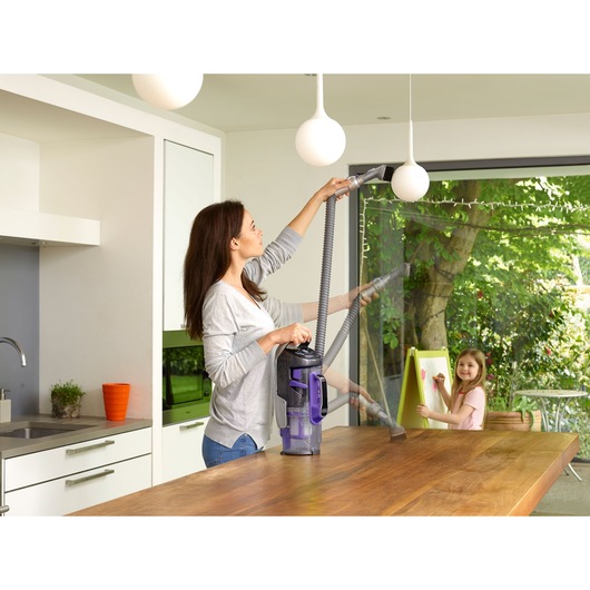 BLACKDECKER CUA525BHP upright vacuum cleaner cleaning a kitchen pendant light and wooden table.