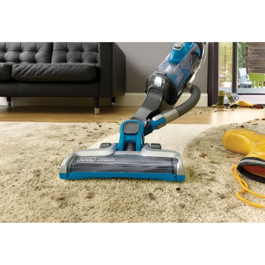 BLACKDECKER CUA525BH cordless vacuum cleaning beige carpet in living room, low front angle.