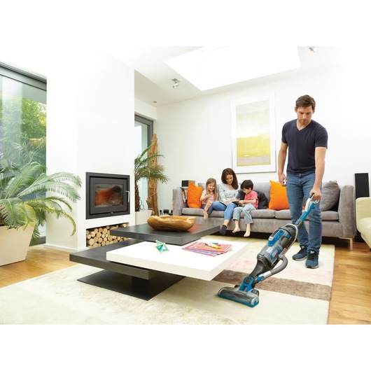 BLACKDECKER CUA525BH vacuum cleaner in use on living room rug, modern sofa and coffee table in background.
