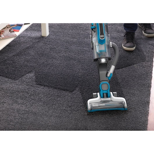 BLACKDECKER CUA525BH upright vacuum cleaner cleaning dark carpet, angled top view.