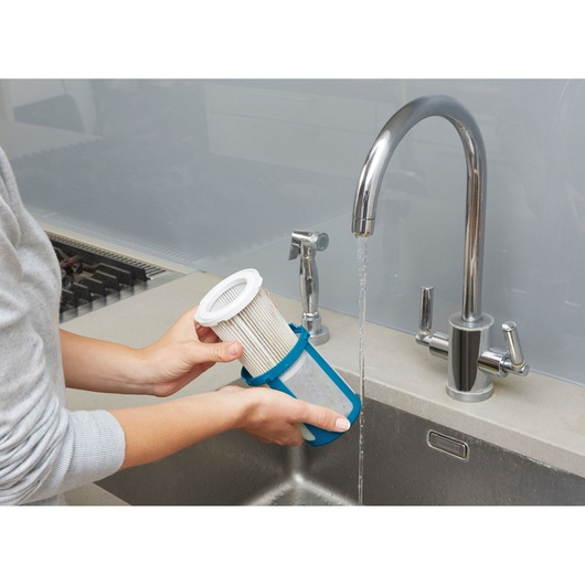BLACKDECKER CUA525BH vacuum filter being washed under a kitchen sink faucet, close-up photography.