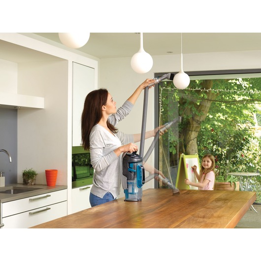 BLACKDECKER CUA525BH vacuum cleaner used in a kitchen to clean light fixtures and surfaces with hose attachment.