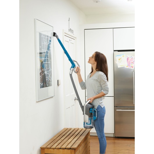BLACKDECKER CUA525BH cordless vacuum cleaner with long blue extension cleaning a wall frame in a kitchen.