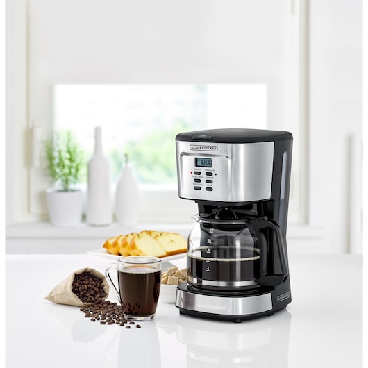 BLACKDECKER DCM85 coffee maker with glass carafe and digital display in kitchen setting, coffee and bread nearby.