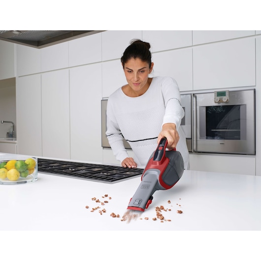 BLACK+DECKER DVJ315J handheld vacuum cleaning crumbs on a white kitchen counter.