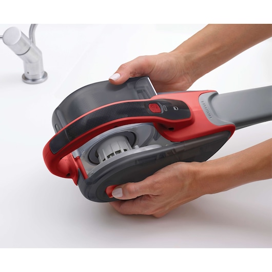 Photo of BLACKDECKER DVJ315J handheld vacuum cleaner held in hands with dust container detached.