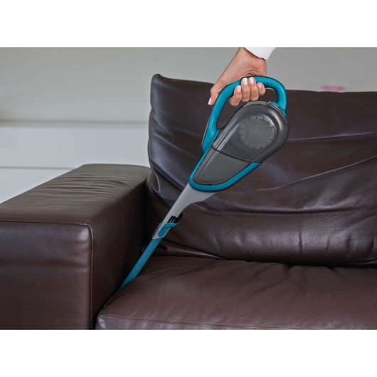 BLACKDECKER DVJ320J handheld vacuum cleaning brown sofa cushion in home setting.