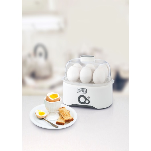 Photo of BLACKDECKER EG200 egg cooker with white eggs and plate of soft-boiled egg and toast on kitchen counter.
