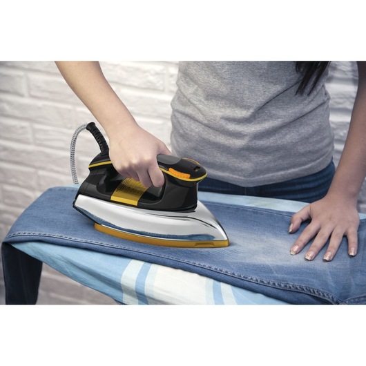 BLACKDECKER F550 steam iron in black and yellow used on denim jeans, close-up photography.