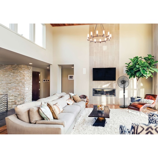 BLACKDECKER FS1620R pedestal fan in modern living room, near fireplace and TV, light wood floors, bright decor.
