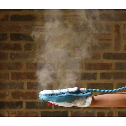 BLACKDECKER FSH10SMP steam cleaning glove emitting steam, close-up side angle against brick wall.