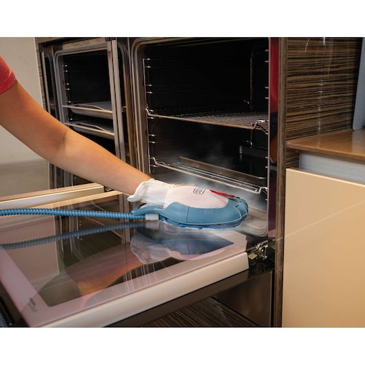BLACKDECKER FSH10SMP steam cleaning glove used to clean oven door in kitchen setting.