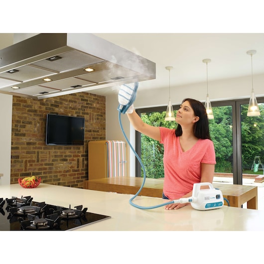 BLACKDECKER FSH10SMP steam cleaner being used to clean a kitchen range hood in a modern kitchen.