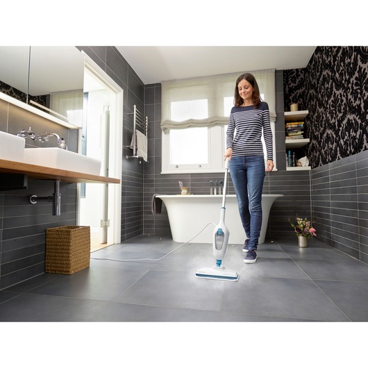 BLACKDECKER FSM13E1 steam mop cleaning dark tile bathroom floor, person using product near bathtub.