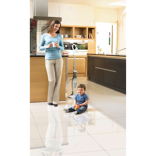BLACKDECKER FSM1630 steam mop on tile floor in modern kitchen, woman standing, child sitting nearby.