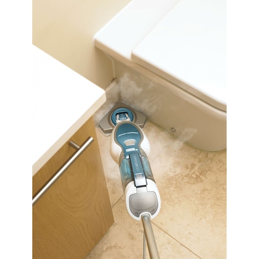 BLACKDECKER FSM1630 steam mop cleaning beige tile floor near a toilet and cabinet, angled from above.