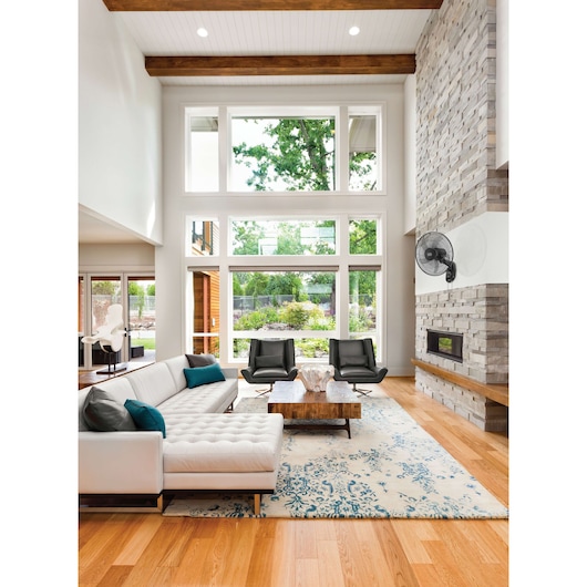 BLACKDECKER FW1620 black oscillating wall fan mounted in modern living room, left side view.