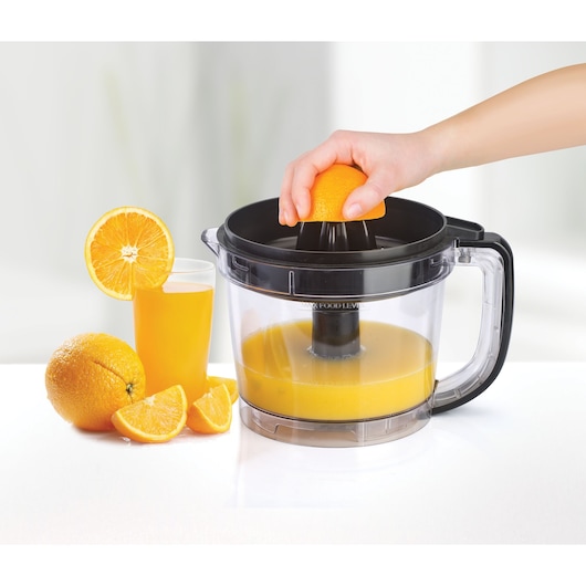 BLACKDECKER FX810 juicer on white background, hand juicing orange, glass of juice and fresh oranges beside.