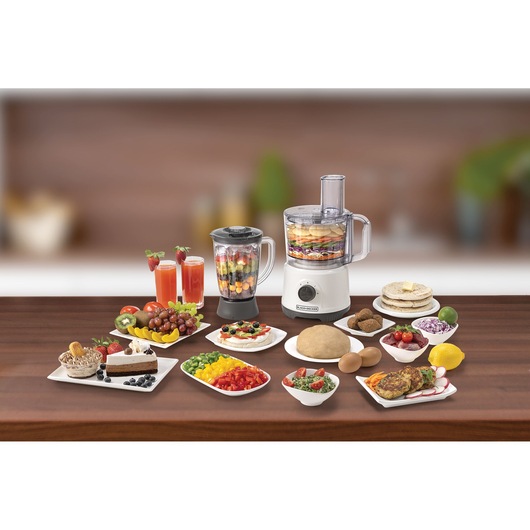 BLACKDECKER FX822 food processor and blender on table with assorted fruits, vegetables, drinks, and prepared dishes.
