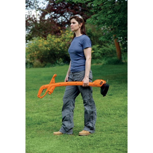 Photo of BLACKDECKER GL360 orange grass trimmer held by a person on a green lawn.