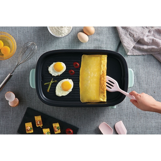 BLACKDECKER GMF1400 electric griddle top view with eggs, omelette, and vegetables cooking, utensils and ingredients nearby.