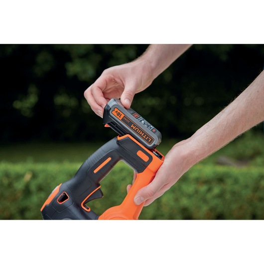 Photo of BLACKDECKER GTC18452PCB 18V lithium battery being inserted into cordless tool outdoors.