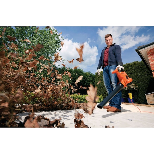 BLACKDECKER GW3030 leaf blower in use clearing dry leaves outdoors.
