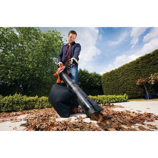 BLACKDECKER GW3030 leaf blower used outdoors with vacuum bag collecting dry leaves on patio.