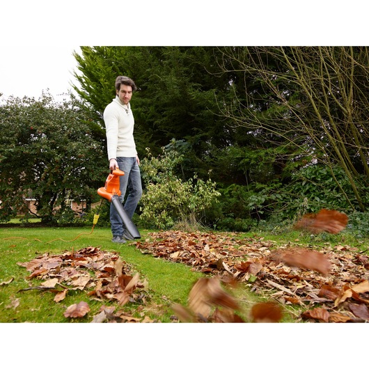 BLACKDECKER GW3031BP leaf blower in use outdoors, orange and black, clearing leaves on grass.