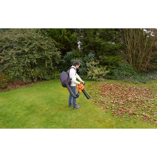 BLACKDECKER GW3031BP leaf blower used outdoors, man with backpack collecting leaves on grass.