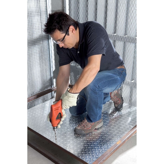 Photo of BLACKDECKER HD5010A5 corded drill used on metal flooring, worker kneeling wearing gloves and boots.