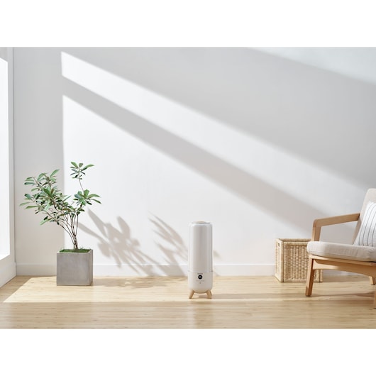BLACKDECKER HM6000 air purifier on wooden floor in bright, minimalist living room with a potted plant and armchair.