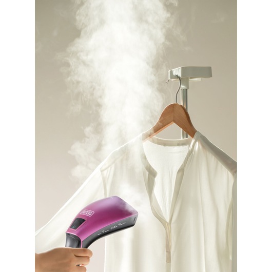 BLACKDECKER HSTD1600 handheld garment steamer in purple used to steam a white shirt on hanger, front view.