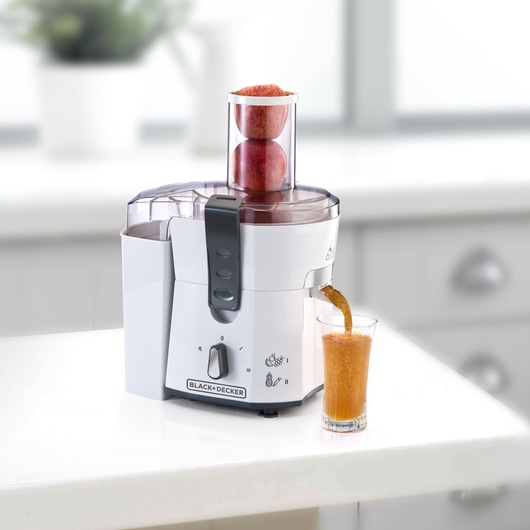 Photo of BLACK+DECKER JE500 juicer extracting apple juice into a glass on a kitchen counter.
