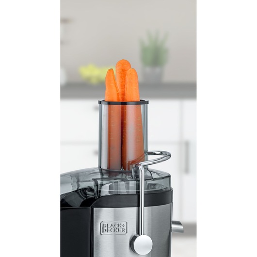 BLACKDECKER JE800 juicer with carrots in feed chute, close-up on stainless steel body, kitchen background.