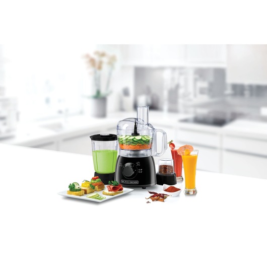 BLACKDECKER KR42 food processor with blender and accessories on a kitchen counter, filled with fresh ingredients.