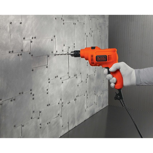 BLACKDECKER KR5010 orange corded drill held against a metal wall, side angle.