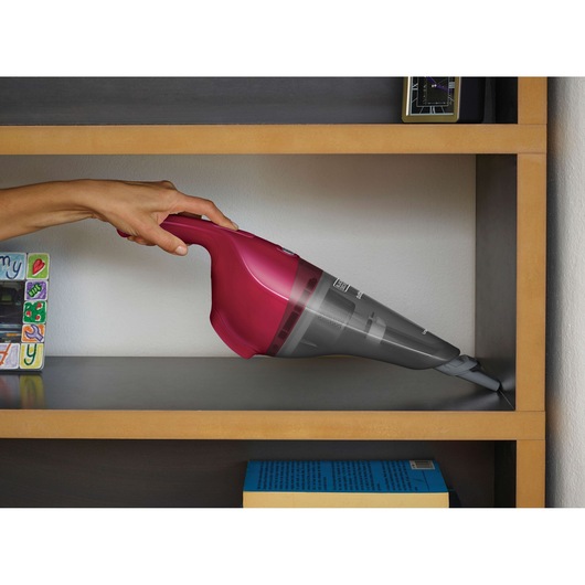 BLACKDECKER NVB115WA handheld vacuum cleaner in magenta used to clean a shelf corner.