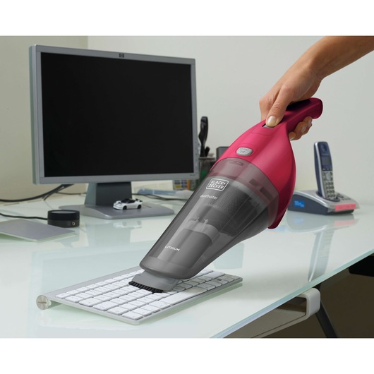 BLACKDECKER NVB115WA handheld vacuum cleaning a keyboard on an office desk.