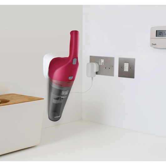 BLACKDECKER NVB115WA cordless handheld vacuum in red and black charging on wall mount in a modern kitchen.