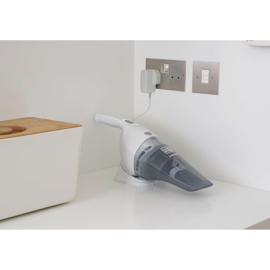 BLACKDECKER NVB215WN handheld vacuum resting on a charging base in a white kitchen corner.
