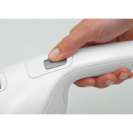 Close-up photo of a hand pressing the power button on a white BLACKDECKER handheld vacuum NVB215WN.