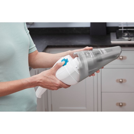 Photo of BLACK+DECKER NVC115JL handheld vacuum being opened by hand in a kitchen setting.