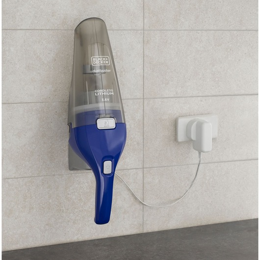 BLACK+DECKER NVC115WA handheld cordless vacuum with blue handle mounted on wall and charging via white plug.